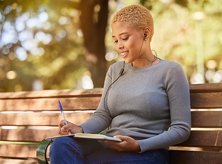 Image showing Woman, earphone and writing in book, diary or journal in a park outdoor with a happy smile on a bench. Latino girl write idea, goals and vision in a notebook in summer while relax or smiling alone