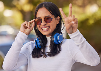 Image showing Music, headphones and peace hand sign of a woman from mexico in nature on a walk. Portrait of a person with a happy smile, sunglasses and gesture streaming audio outdoor feeling free in a nature park