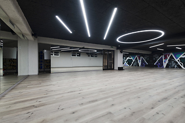 Image showing An empty dance hall with a glass wall adorned with decorative graffiti, offering a fusion of contemporary, urban artistic ambiance and impressive aesthetics.