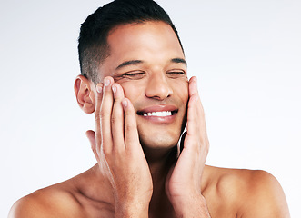 Image showing Face, beauty and skincare with a man grooming in studio on a gray background for health or wellness. Happy, cosmetics and antiaging with a handsome young male touching is soft or smooth skin