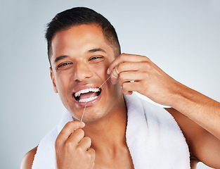 Image showing Man, dental flossing and teeth with smile for clean hygiene and health against a grey studio background. Portrait of happy toothy male smiling in fresh grooming and floss for mouth, oral and gum care