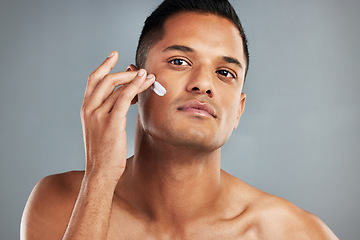 Image showing Beauty, skincare and man with cream on his face using skincare products, lotion and moisturizer. Facial, wellness and healthy skin of young male with beauty products for men in grey background studio