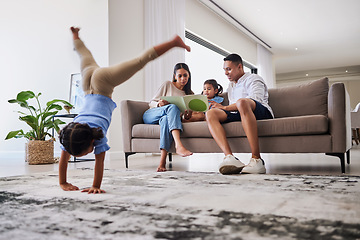 Image showing Handstand, children and parents reading a book to their child together in their house. Mother, father and kids bonding with a story, playing and relax in the living room of their family home