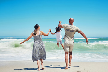 Image showing Beach, holding hands and family lifting child in the air, having fun, playing and enjoying the waves. Travel, summer and love on vacation with mom, dad and young girl together by the ocean on holiday