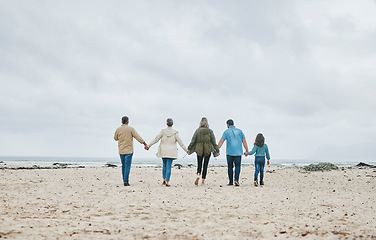 Image showing Big family, beach holiday and summer travel with child, parents and grandparents on sand and cloudy sky for love, care and support. Men, women and girl kid walking together holding hands on vacation