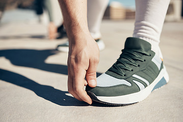 Image showing Shoes, hand and stretching with a sports man touching his toes during an exercise or fitness warmup in the city. Health, training and workout with a male athlete getting ready for competition closeup