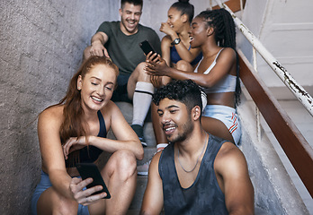 Image showing Fitness, phone and group of friends on stairs networking on social media together after gym workout. Happy, smile and sports people sitting and watching funny comic videos on internet with smartphone