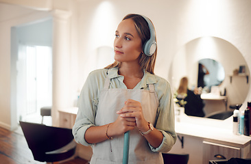 Image showing Cleaning, sweeping and salon with a woman cleaner listening to music while working with a broom. Idea, headphones and streaming audio with a female at work in a hairdresser for hygiene or cleanliness