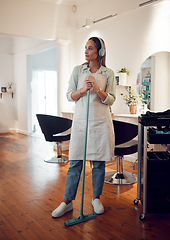 Image showing Salon, headphones and woman cleaner sweeping her workplace while listening to music, radio or podcast. Broom, cleaning and girl maid doing domestic work in a beauty parlor while streaming audio.