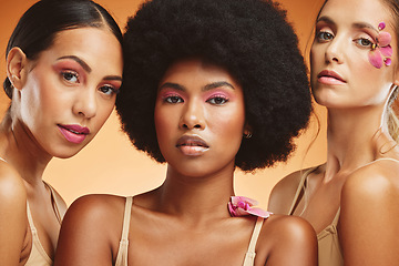 Image showing Diversity, beauty and women with flowers for makeup, skincare and cosmetics. Skincare products, spa wellness and group of girls portrait in orange studio with pink orchids for natural beauty products