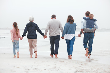 Image showing Holding hands, walking and big family on the beach for exercise while on summer vacation. Grandparents, parents and children on outdoor walk in nature by ocean while on holiday, adventure or journey.