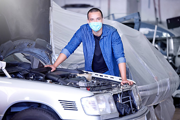 Image showing Car, face mask and a mechanic in workshop during covid, safety, and insurance at work. Working, maintenance and quality assurance, man in a garage with vehicle and small business car mechanic startup