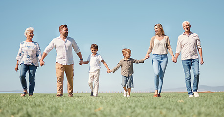 Image showing Family, love and walking with smile, together and happy on a field in nature with a blue sky background. Big family with kids, parents and grandparents enjoy weekend, holiday and summer in Germany