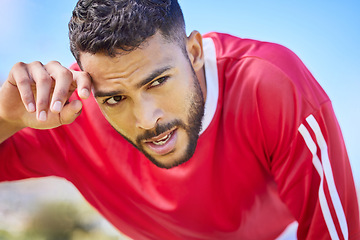 Image showing Soccer, sports and tired young athlete at a game, training or workout on an outdoor field. Fitness, exercise and healthy man player taking breathe while playing football match on pitch at the stadium