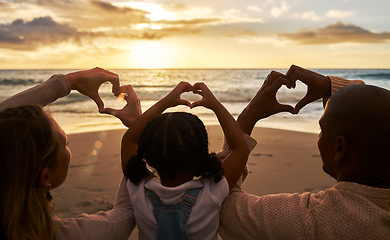 Image showing Beach, heart hands and family for love of summer, ocean and outdoor wellness with parents, child and sunset sky clouds . Behind of people, or mother and father with kid with care sign or icon for sea