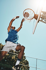 Image showing Basketball, sport and man with a goal during a game, professional event or training on an outdoor court in summer. Low view of an athlete in the air to score during sports for fitness and exercise