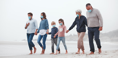 Image showing Big family, covid and holding hands walking on beach for quality bonding time together during pandemic in nature. Hand of parents, grandparents and kids in travel, freedom and family walk with masks