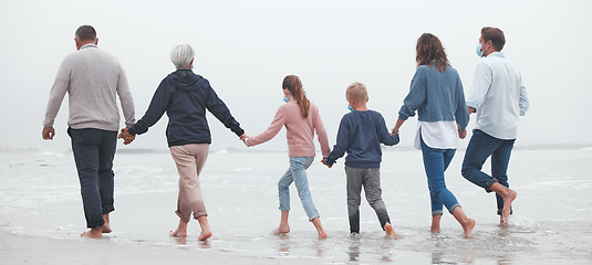 Image showing Big family, holding hands and walking on beach for vacation or quality bonding time together in nature. Hand of parents, grandparents and kids enjoying travel, freedom and family fun in ocean water