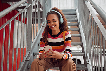 Image showing Phone, headphones and black woman on stairs in city streaming music, audio or radio. Gen z, earphones and Brazilian student on 5g mobile, texting or internet surfing, social media or web browsing.