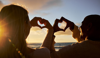 Image showing Heart hands, love and couple on beach for summer, outdoor health and wellness with sunset sky and silhouette. Happy woman or people with care sign for ocean, sea holiday or vacation together