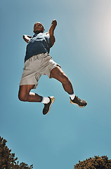 Image showing Sports, blue sky and basketball man jump for game, competition or slam dunk training, practice or workout. High energy, athlete motivation and basketball player doing fitness or exercise bottom view