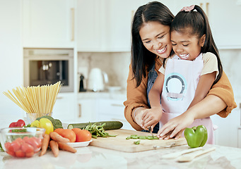 Image showing Happy, mother and child learning to cook with smile for help, guidance and support in the kitchen. Mama helping her little girl cut vegetables, food or meal for healthy diet and fun bonding at home