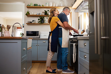 Image showing Love, food and elderly couple cooking in a kitchen, hug and bond while preparing a meal in their home together. Happy family, retirement and mature man and woman embrace while preparing a meal