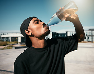 Image showing City heat, summer and black man drinking water on concrete road, thirsty gen z outdoor activity. Sun, fun and urban young man with healthy street culture lifestyle and clean water in bottle to drink.