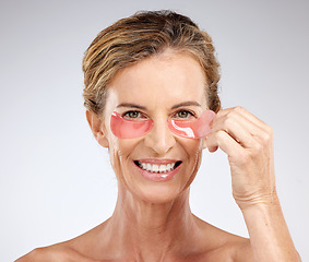 Image showing Eye patches, cosmetics and senior woman being happy, smile and wellness with skincare, health and studio background. Portrait, makeup and mature female with organic facial. for eye care and healthy.