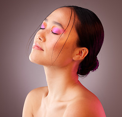 Image showing Beauty, makeup and woman with neon cosmetics on her face against a grey mockup studio background. Relax, calm and Asian model with peace from luxury pink facial cosmetic and skincare wellness