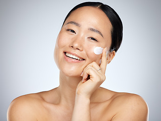 Image showing Face, skincare and beauty with a model asian woman applying lotion or moisturizer to her skin in studio. Cosmetics, antiaging and wellness with a young female inside to promote a skin product