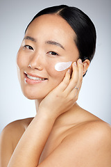 Image showing Face, beauty and skincare with an model asian woman in studio on a gray background for wellness. Luxury, health and cosmetics with a young female using an antiaging product or lotion treatment