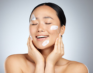 Image showing Beauty, skincare and facial product with woman and cream on face for wellness, spa and clean. Sunscreen, cosmetics and health with asian girl for luxury, salon and model lifestyle in gray background