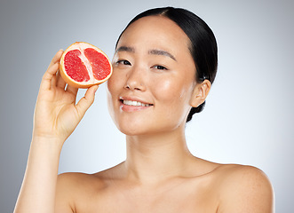 Image showing Grapefruit, skincare and woman with food for face, wellness and beauty against a grey mockup studio background. Portrait of young, happy and Asian model with fruit for nutrition, diet and body health