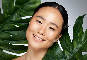 Image showing Face, beauty and asian woman with monstera leaf on gray studio background. A beautiful Japanese woman with healthy, glowing and flawless skin, skincare routine and makeup with organic plant cosmetics