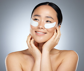 Image showing Beauty, skincare and woman using eye patch, face mask or dermatology product against mockup studio background. Happy asian girl model using facial cosmetics on skin for a healthy glow with collagen