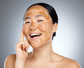 Image showing Skincare, portrait and woman with a coffee face mask for fresh, clean and beautiful skin in studio. Beauty, dermatology and happy girl model from Japan with facial scrub isolated by a gray background