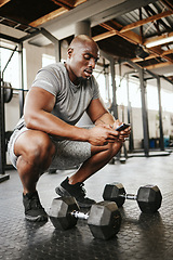 Image showing Fitness, phone and online personal trainer at the gym typing or searching on social media in Nigeria. Strong black man, bodybuilder and healthy sportsman networking or texting a digital message