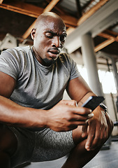 Image showing Phone, fitness and sweat with a black man athlete checking his social media after a workout or exercise at the gym. Training, mobile and health with a male tracking his progress on an internet app