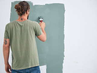 Image showing Painting, brush and renovation with a man doing interior DIY in a room for improvement and remodel of home. Young man, decoration and work with green paint on a wall to maintenance in domestic house