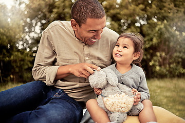 Image showing Father, girl and popcorn eating of a happy child and parent outdoor laughing with a smile. Dad, happiness and kid with food hug together with bonding, quality time and nature experience having fun