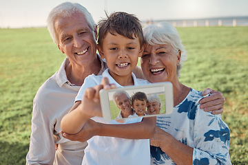 Image showing Phone, selfie and happy grandparents with child outdoor in nature on family picnic together. Happiness, smile and elderly man and woman in retirement taking picture on smartphone with boy grandchild.
