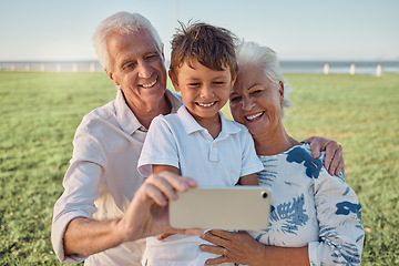 Image showing Kid, grandparents and phone selfie on grass in park spending time together on the weekend. Grandma, grandpa and boy child with smile on face, happy family take outdoor portrait on smartphone on field