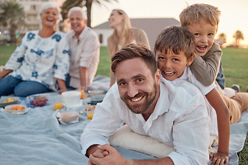 Image showing Family picnic in garden, father with kids in outdoor park and healthy food for snack with grandparents support. Children playing with dad on grass, parents on weekend and big family vacation together