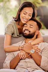 Image showing Happy, love and hug with a black couple on the sofa to relax in the living room of the home together. Smile, happy and hugging with a male and female bonding in the lounge of their house for romance