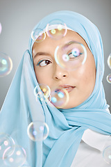 Image showing Skincare, bubbles and Muslim model with beauty, idea and thinking against a grey studio background. Young, Islamic and cosmetic woman with a hijab, makeup and vision for dermatology with bubble