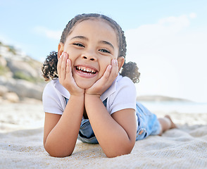 Image showing Child, smile and happiness on beach vacation picnic in summer with a face portrait for smile, fun and summer travel. Girl kid lying in sun on holiday, adventure and playing by the ocean in Florida