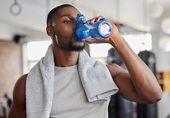 Image showing Water, drink and fitness with a sports man in a gym for exercise while taking a break to hydrate. Workout, training and drinking with a male athlete taking a sip from a bottle after his routine