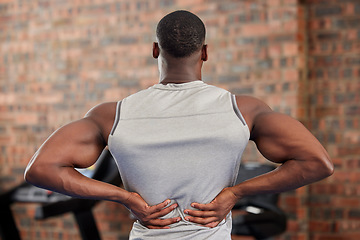 Image showing Back pain, fitness and exercise with a sports man suffering from an injury or inflammation during a workout in the gym. Training, health and anatomy with a male athlete struggling with muscle strain