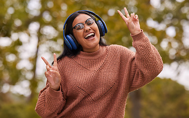 Image showing Music, headphones and peace hand sign of a woman from India in nature on a walk or hike. Portrait of a person with a happy smile listening to a podcast and web streaming audio outdoor feeling free